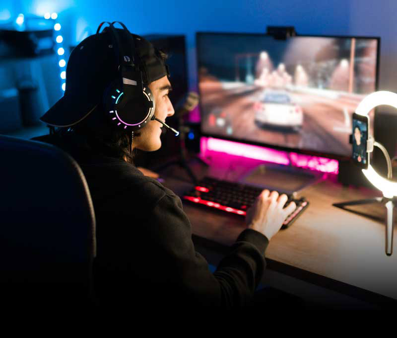 A male wearing a headset is playing a video game while entertaining his audience on a streaming platform.