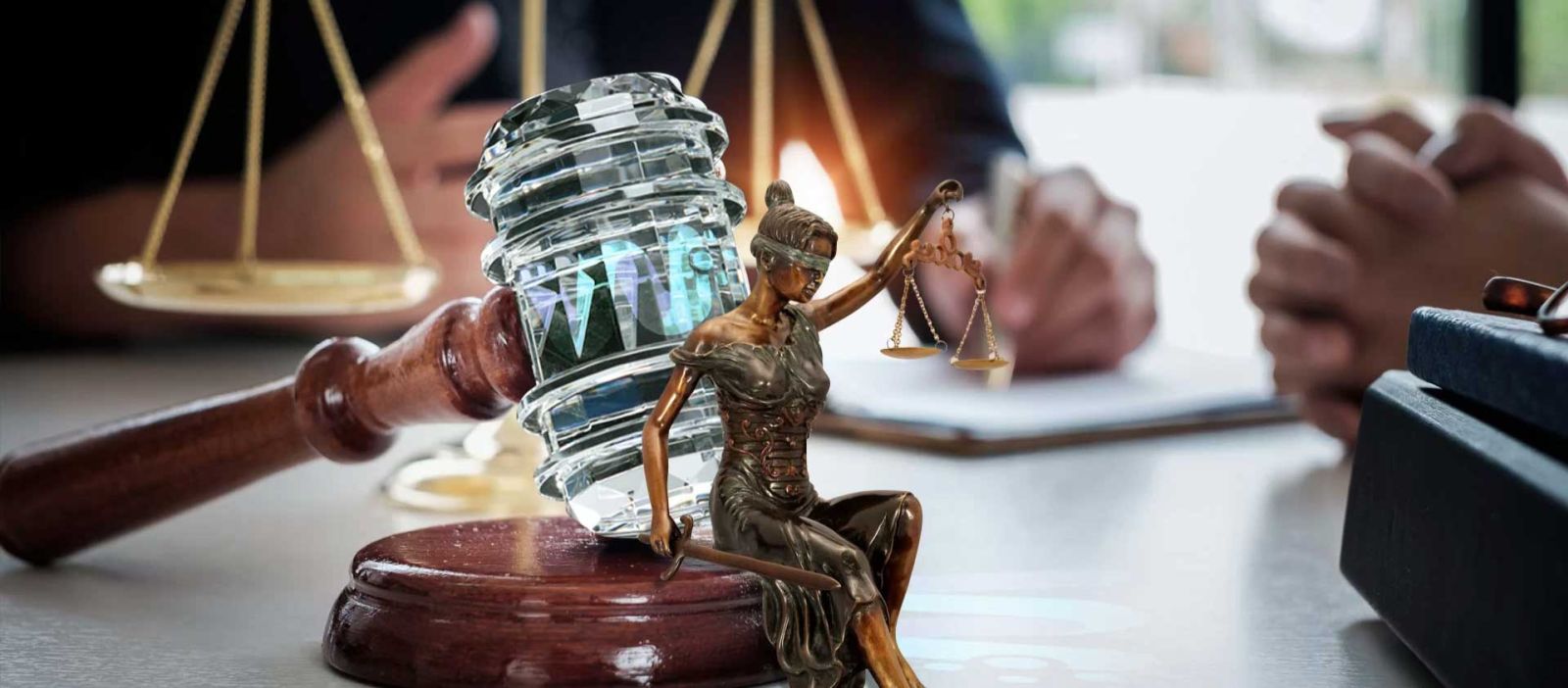 Captured from the viewpoint of a client seated across the desk, the photo showcases a lawyer’s workspace adorned with golden scales, a crystal gavel, and a miniature statue of Lady Justice.