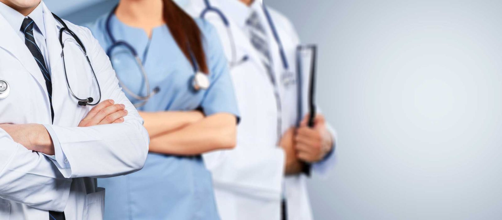 Three doctors, two males and one female, are confidently standing in-line in a brightly lit area.