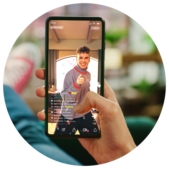 A hand holding a mobile phone displaying a social media video stream where a male influencer is pointing at his audience.