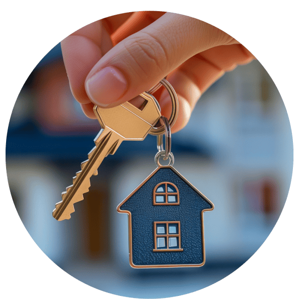 A hand is holding a golden key attached to a keyring with a small house-shaped pendant, and in the background is a well-maintained, two-story home.
