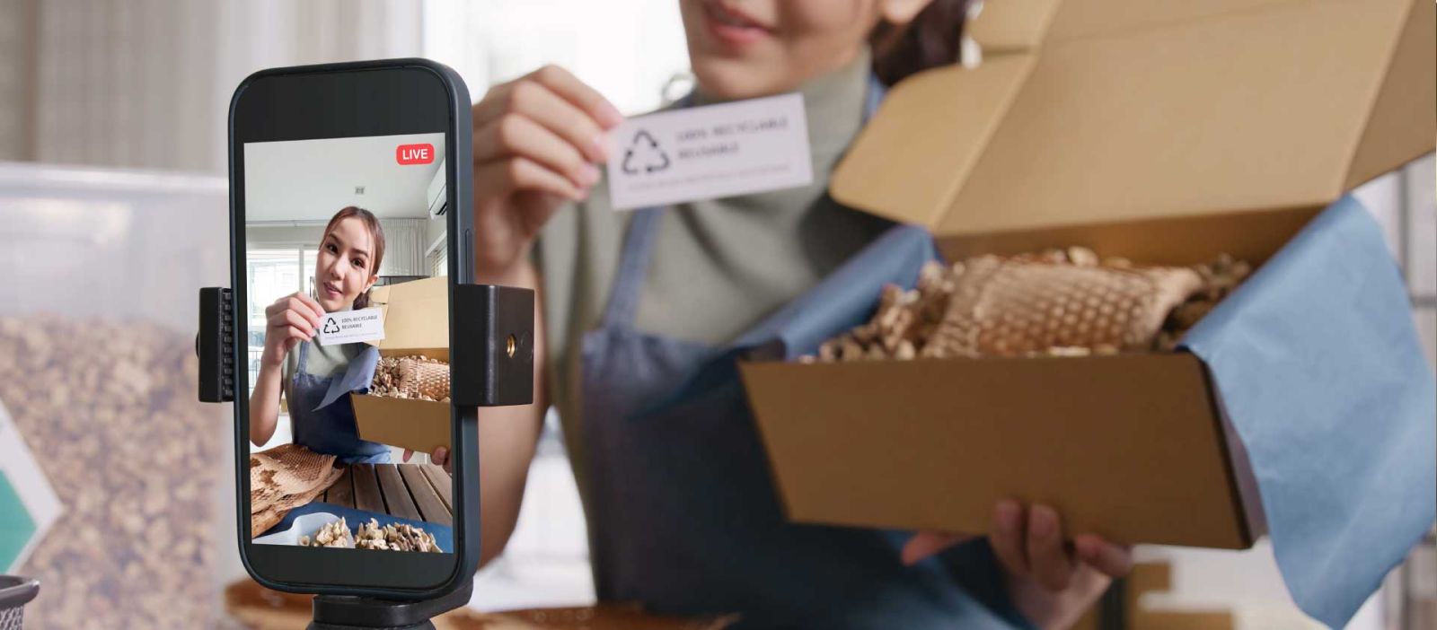 Female influencer streaming live on her mobile phone, showcasing a product and engaging with her audience in real-time.